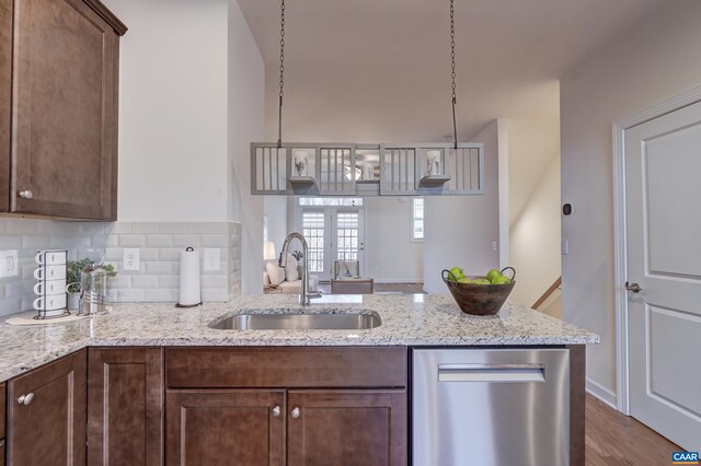 kitchen with light stone counters, stainless steel dishwasher, sink, and hanging light fixtures