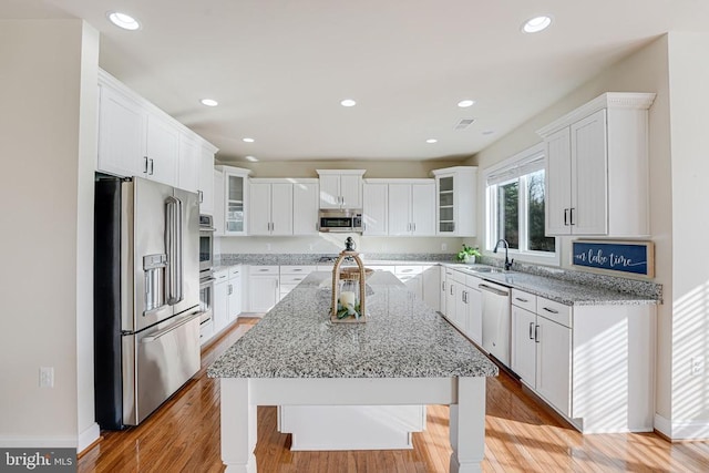 kitchen featuring a sink, a center island with sink, stainless steel appliances, and white cabinetry