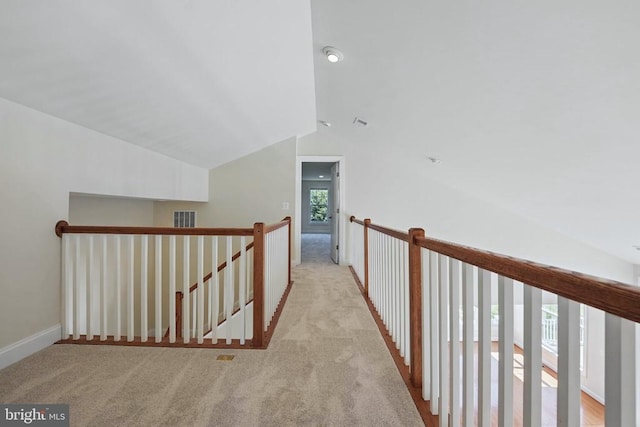 corridor with carpet floors, baseboards, lofted ceiling, and an upstairs landing