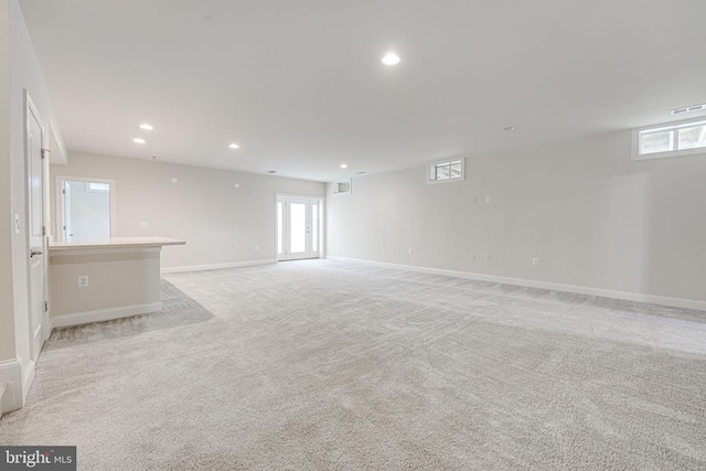 unfurnished living room featuring baseboards, visible vents, recessed lighting, and light colored carpet