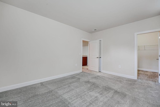 unfurnished bedroom with baseboards, carpet, and a spacious closet