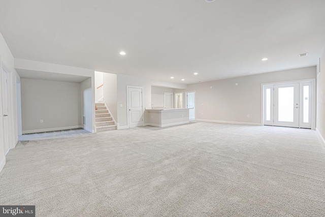 unfurnished living room featuring stairs, recessed lighting, baseboards, and light colored carpet