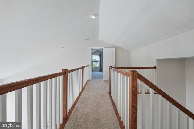 hallway with an upstairs landing, lofted ceiling, and light carpet