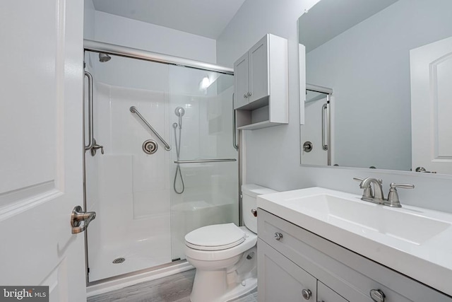 full bath with vanity, toilet, wood finished floors, and a stall shower