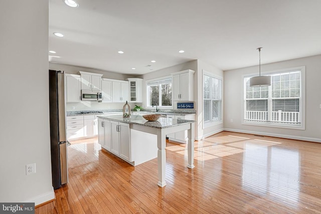 kitchen featuring appliances with stainless steel finishes, baseboards, light wood finished floors, and white cabinetry