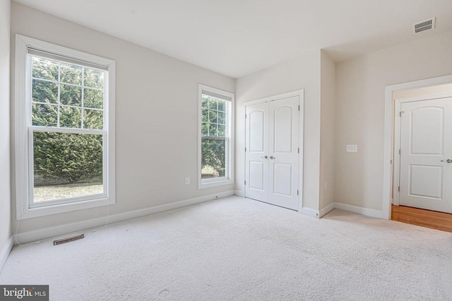 unfurnished bedroom with visible vents, carpet flooring, baseboards, and a closet