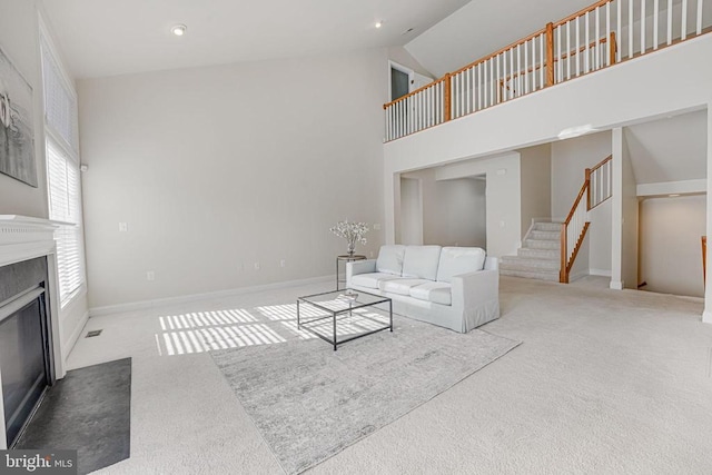 living room featuring a fireplace with flush hearth, high vaulted ceiling, stairway, and carpet