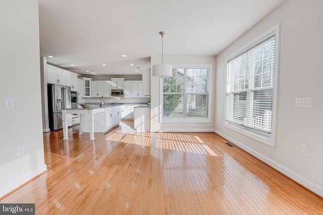 unfurnished living room featuring baseboards, recessed lighting, and light wood-style flooring