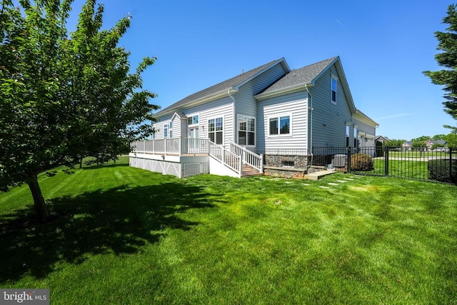 rear view of house featuring fence, a lawn, and a deck