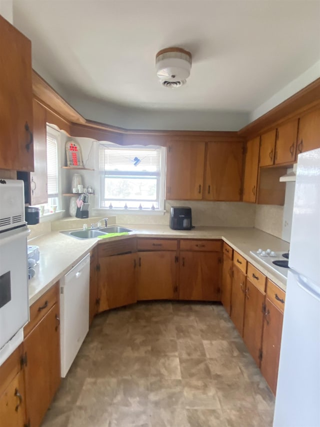 kitchen with brown cabinets, open shelves, light countertops, a sink, and white appliances