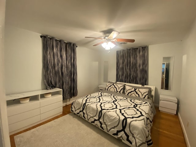 bedroom featuring wood finished floors, a ceiling fan, and baseboards