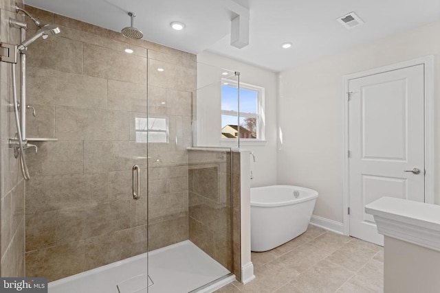 bathroom featuring visible vents, baseboards, a soaking tub, and a stall shower