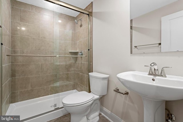 bathroom featuring a sink, baseboards, toilet, and a shower stall