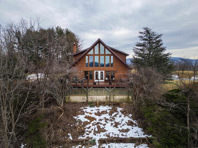 snow covered house featuring a wooden deck