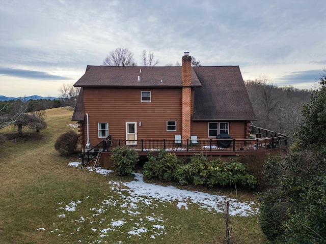 snow covered house featuring a lawn and a deck