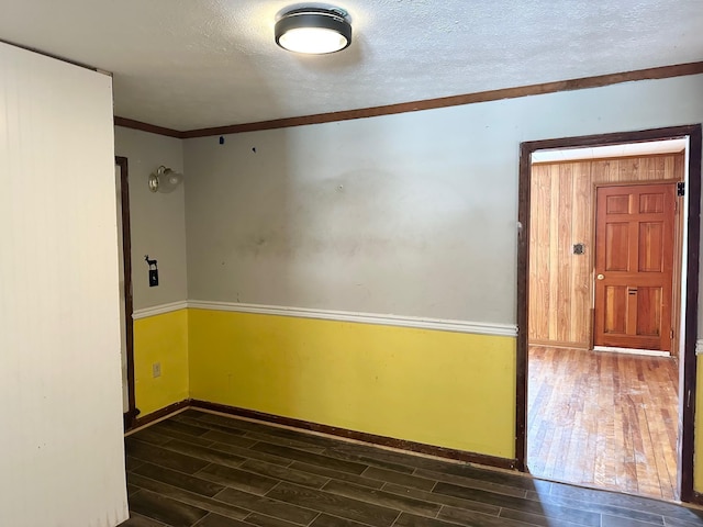 spare room with ornamental molding, a textured ceiling, and dark hardwood / wood-style flooring