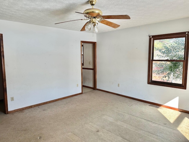 spare room with ceiling fan, light colored carpet, and a textured ceiling