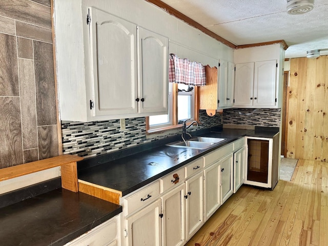 kitchen featuring sink, white cabinets, backsplash, crown molding, and light hardwood / wood-style flooring