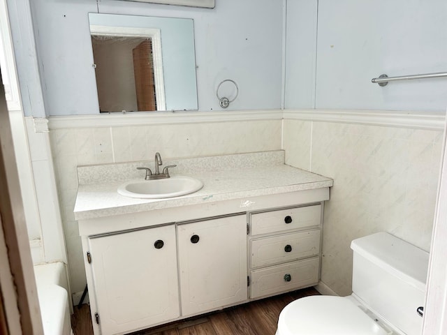 bathroom featuring vanity, wood-type flooring, tile walls, and toilet