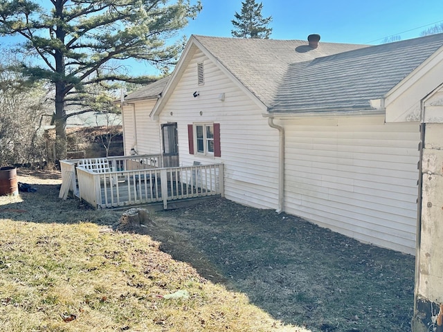 rear view of property featuring roof with shingles and a deck