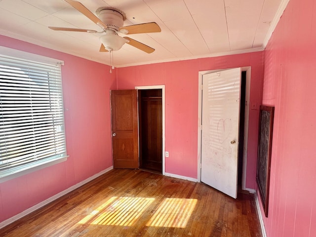 unfurnished bedroom with hardwood / wood-style flooring, baseboards, ornamental molding, and ceiling fan