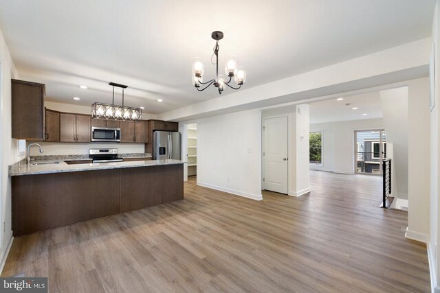 kitchen featuring sink, hanging light fixtures, kitchen peninsula, stainless steel appliances, and light wood-type flooring