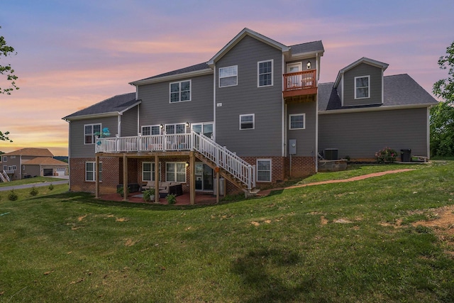 back of property at dusk featuring a patio area, a lawn, stairway, and central air condition unit