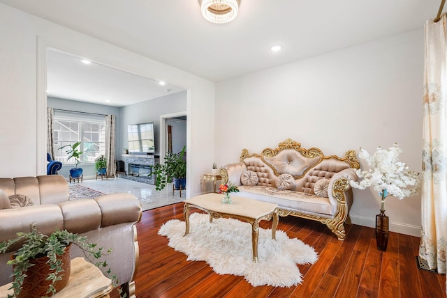 living room featuring recessed lighting, baseboards, dark wood-type flooring, and a glass covered fireplace