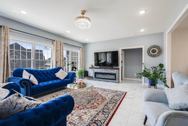 living room featuring recessed lighting, marble finish floor, a glass covered fireplace, and baseboards