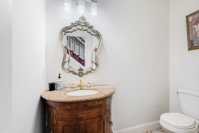 bathroom with toilet, baseboards, and vanity