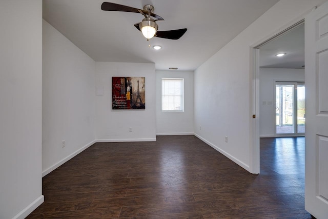 unfurnished room with ceiling fan, dark wood finished floors, and baseboards