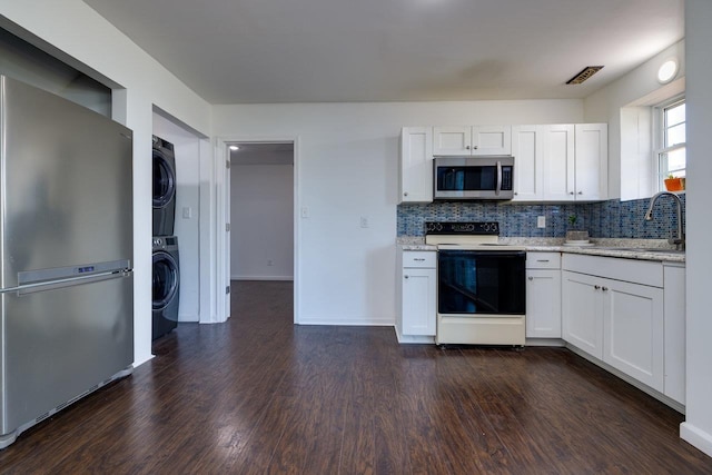 kitchen featuring stainless steel appliances, dark wood-style flooring, white cabinets, and stacked washer / drying machine