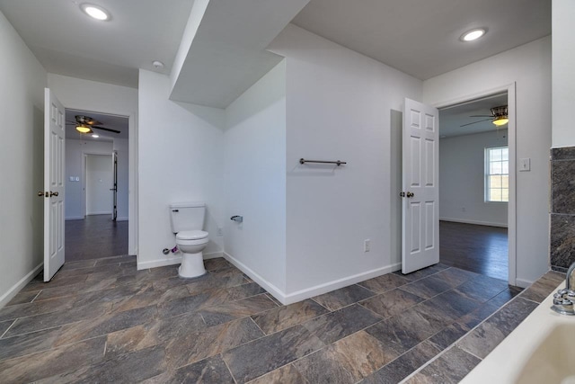 bathroom with stone finish flooring, baseboards, and toilet