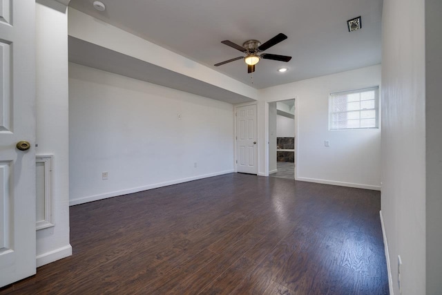 unfurnished room featuring dark wood-style floors, visible vents, baseboards, and a ceiling fan