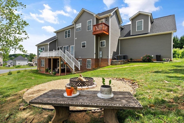 rear view of house featuring stairway, a lawn, a fire pit, and a deck