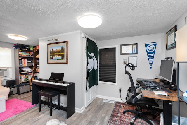 office space featuring cooling unit, a textured ceiling, baseboards, and wood finished floors