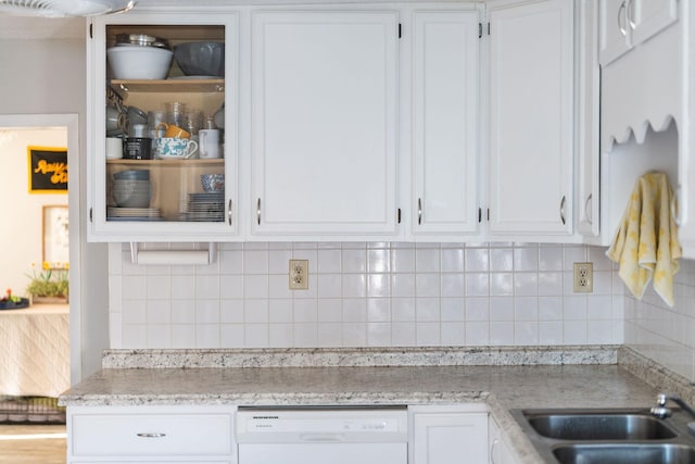 kitchen featuring a sink, white cabinets, dishwasher, tasteful backsplash, and glass insert cabinets