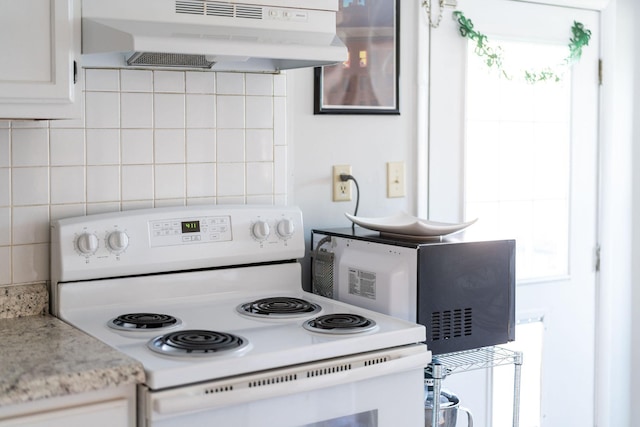 kitchen with under cabinet range hood, plenty of natural light, white electric stove, and tasteful backsplash