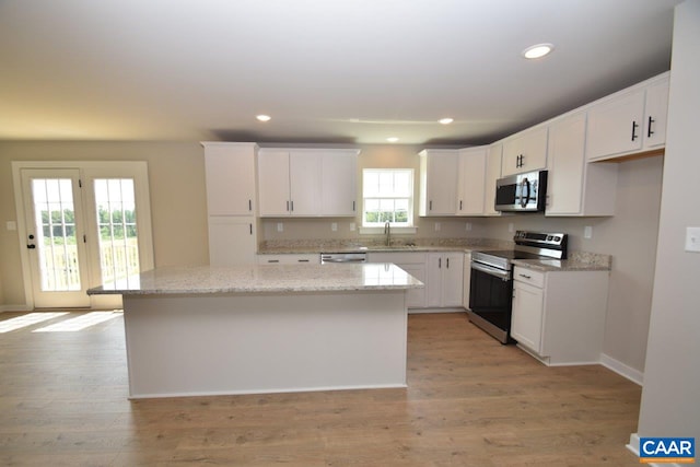 kitchen with light stone countertops, a center island, white cabinets, and appliances with stainless steel finishes