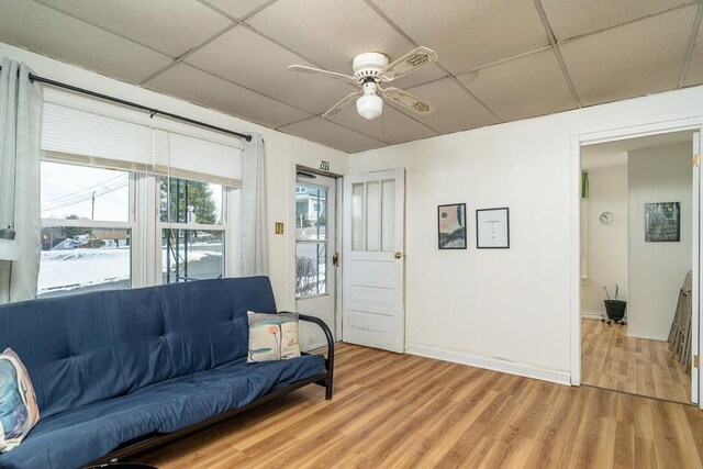 living room featuring a drop ceiling, hardwood / wood-style flooring, and ceiling fan