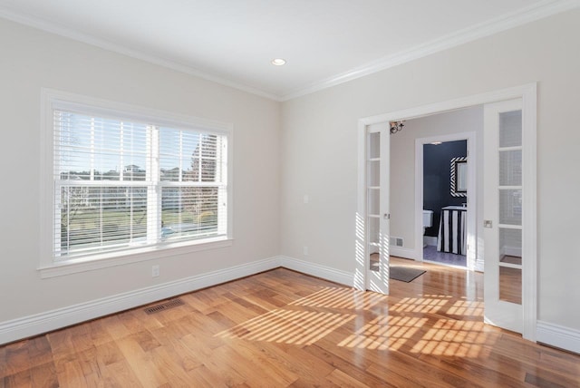 empty room featuring french doors, ornamental molding, and light hardwood / wood-style flooring