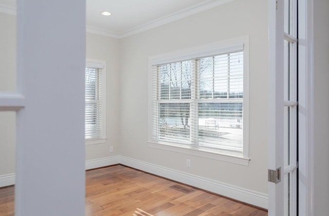 spare room featuring ornamental molding and light wood-type flooring