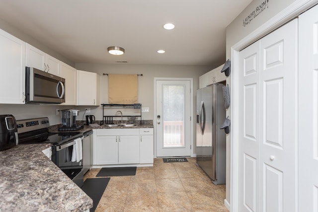 kitchen featuring dark stone countertops, recessed lighting, appliances with stainless steel finishes, white cabinetry, and a sink