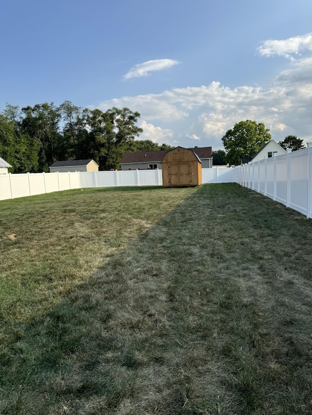 view of yard featuring an outdoor structure, a fenced backyard, and a shed