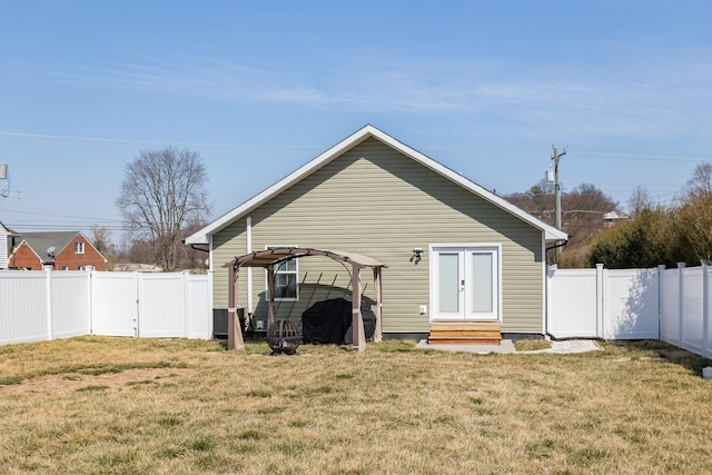 rear view of house featuring a lawn, entry steps, and a fenced backyard