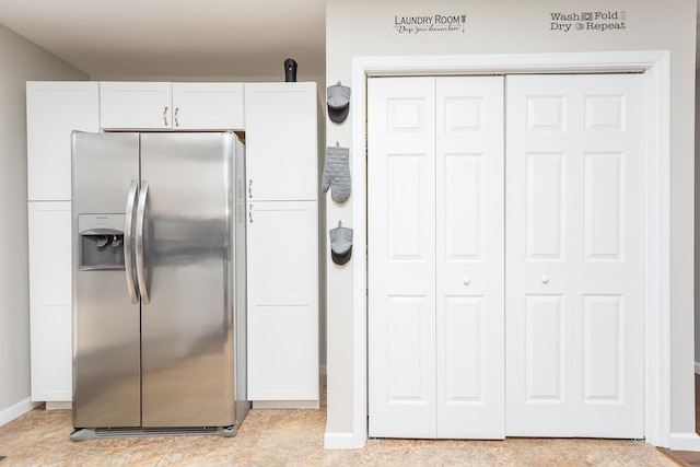 kitchen featuring baseboards, white cabinetry, and stainless steel refrigerator with ice dispenser