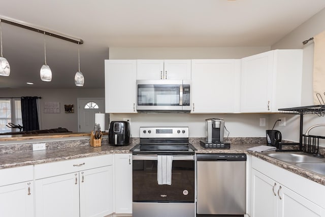 kitchen featuring a sink, appliances with stainless steel finishes, hanging light fixtures, and white cabinetry