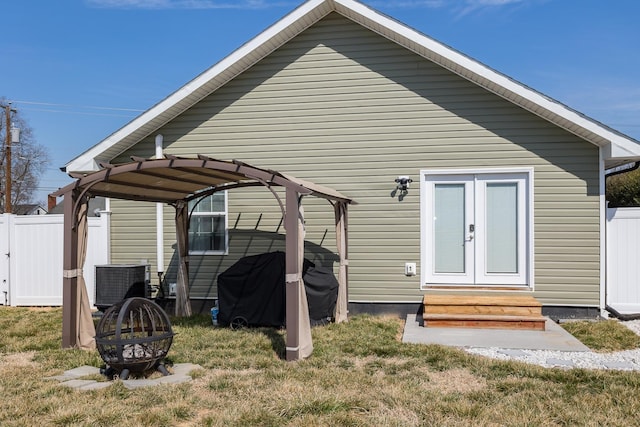 rear view of property featuring entry steps, fence, central AC, and a fire pit