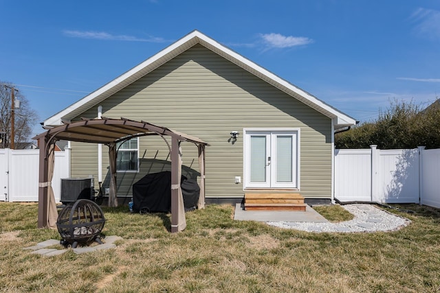 rear view of house featuring a fire pit, fence, entry steps, central AC unit, and a gate