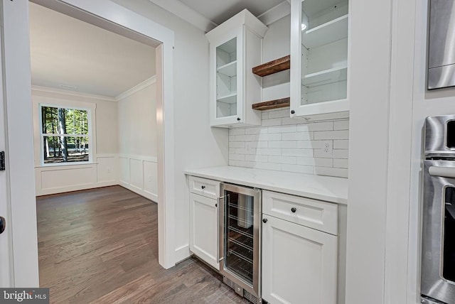 bar with wine cooler, ornamental molding, dark wood-type flooring, and white cabinets